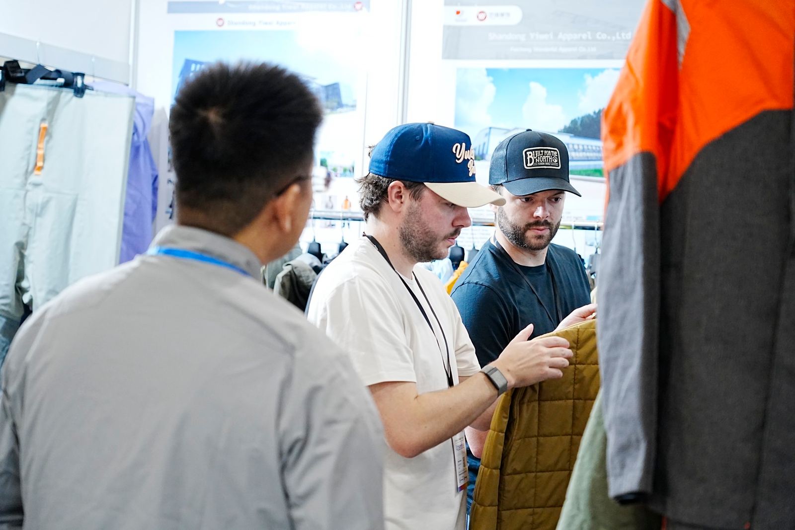Buyers examining a quilted jacket with a supplier at a booth